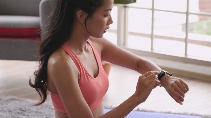 女性在家锻炼后使用智能手表测量心率