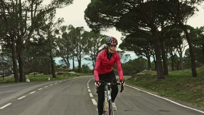 女自行车手在海岸公路上坡骑车