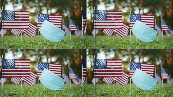 美国的几面小旗上戴着外科口罩在风中飘扬
