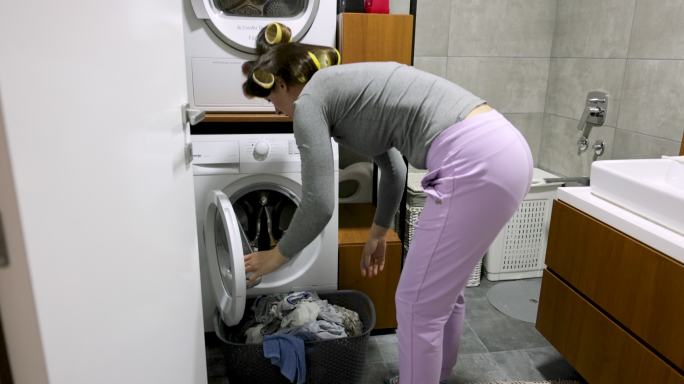 家庭主妇从洗衣机里拿出衣服时感到背部疼痛