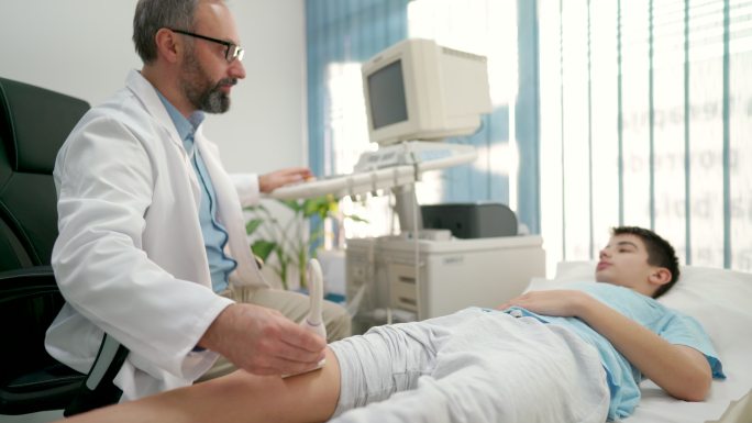 医生用超声波诊断男孩的膝盖状况