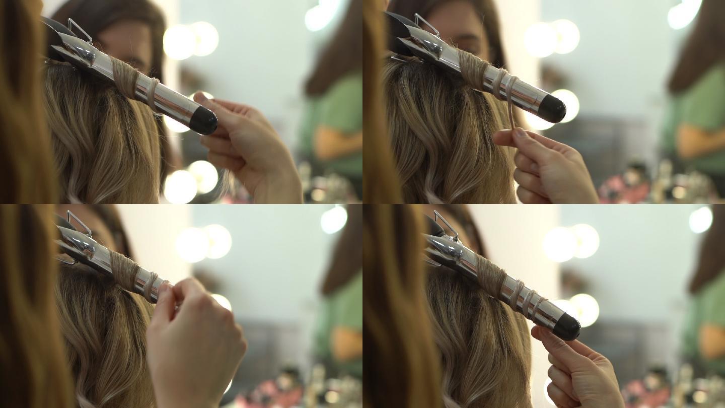 发型师用卷发钳做发型的特写镜头。