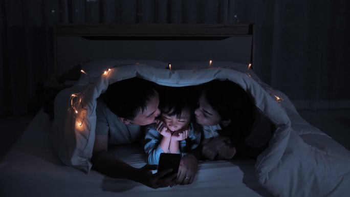 家庭晚上在家里的床上使用智能手机