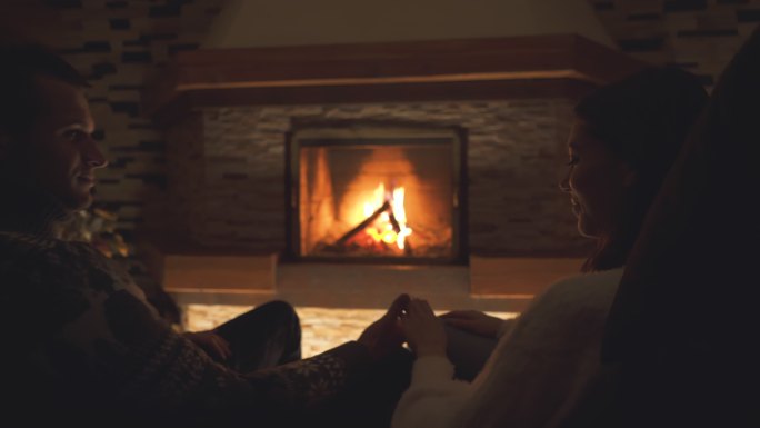 坐在壁炉旁的幸福的年轻夫妇