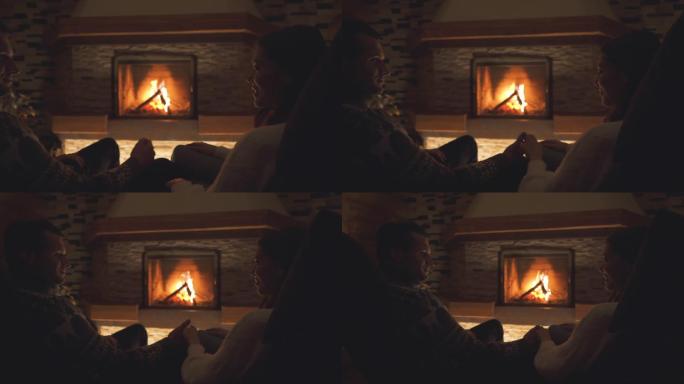 坐在壁炉旁的幸福的年轻夫妇