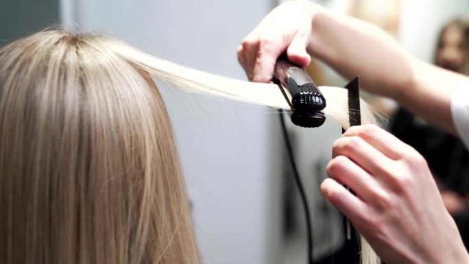 美发师用直发器给女人的长发定型