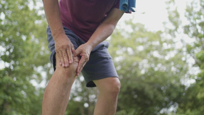 男性在公园慢跑运动中膝盖受伤疼痛