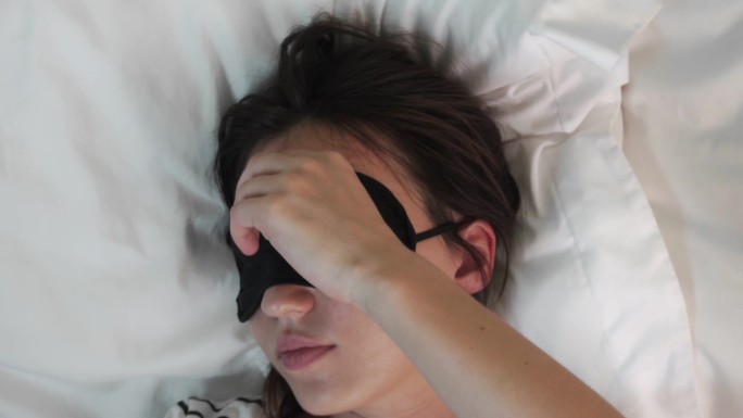 年轻女子在床上休息时戴着眼罩
