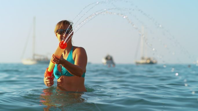 快乐的女人在暑假玩水枪。