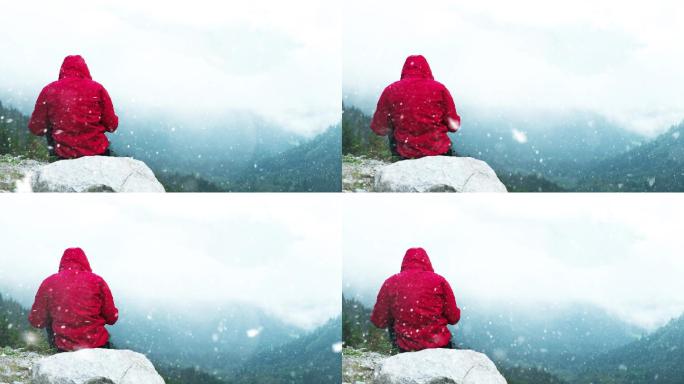 男人下雪天坐在山顶上