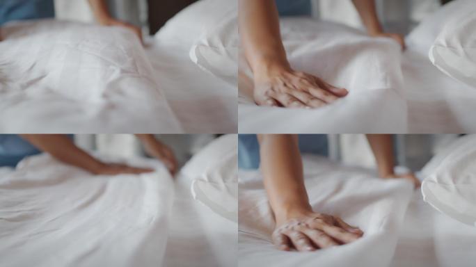 一名妇女在早上醒来后在卧室整理毯子和被褥