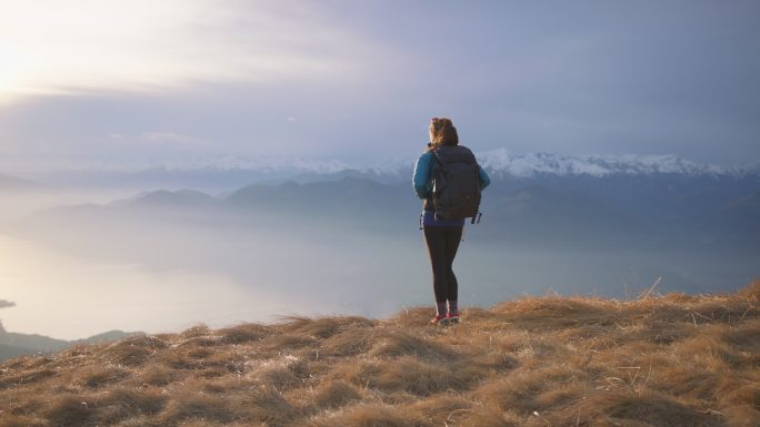 女徒步旅行者站在山顶欣赏日落