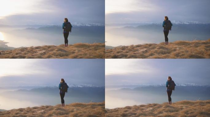 女徒步旅行者站在山顶欣赏日落