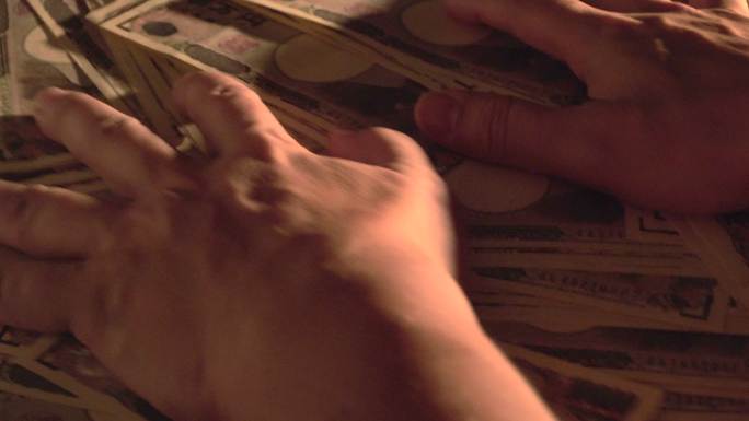 双手把桌上的一万日元钞票从屏幕上拿走了