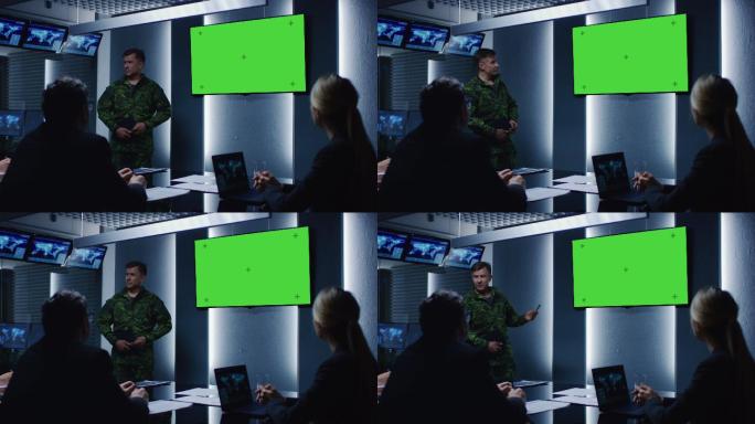 军官做简报，指着绿色的模拟屏幕墙壁电视
