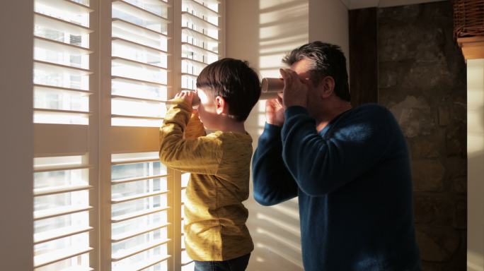 孙子和祖父在家里用卫生纸看窗外