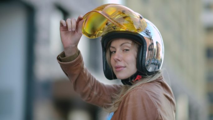 穿着皮夹克的女人摘下摩托车头盔