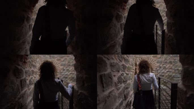 年轻的女旅行者穿过堡垒的墙壁探索