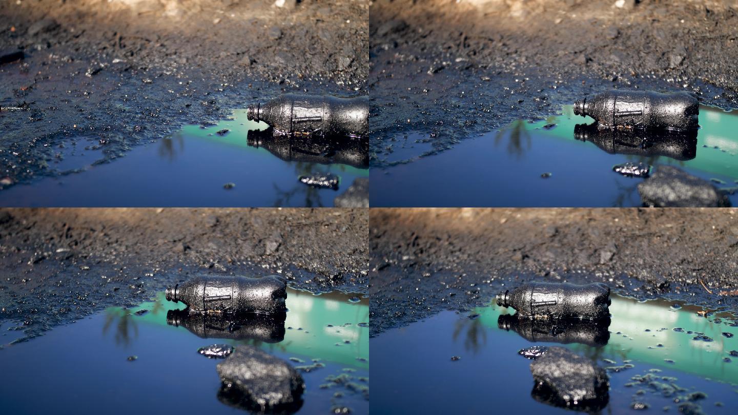 黑色油或柴油废水坑中的塑料瓶