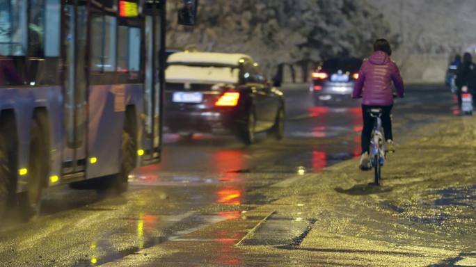 城市晚上，雨雪道路，公交车驶过，共享单车