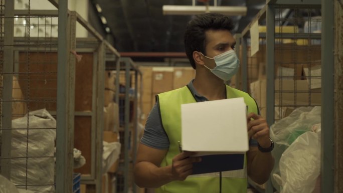 仓库工人在工作时戴着防护面罩整理货物