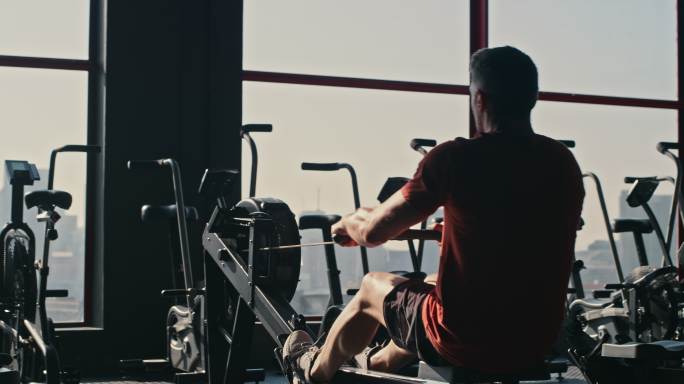 一个男子在健身房锻炼时使用划船机