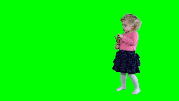 小女孩在绿色背景下玩木制拨浪鼓玩具