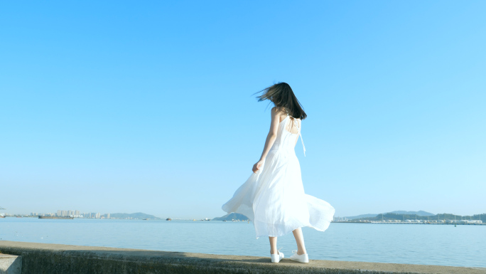 穿白色吊带长裙的女孩在江边吹风转圈素材