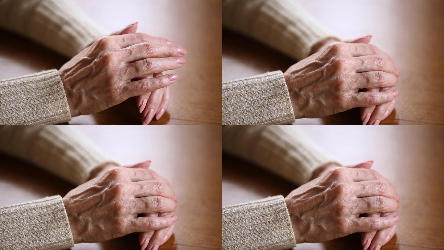 老妇人皱着的手叠在桌子上的特写镜头