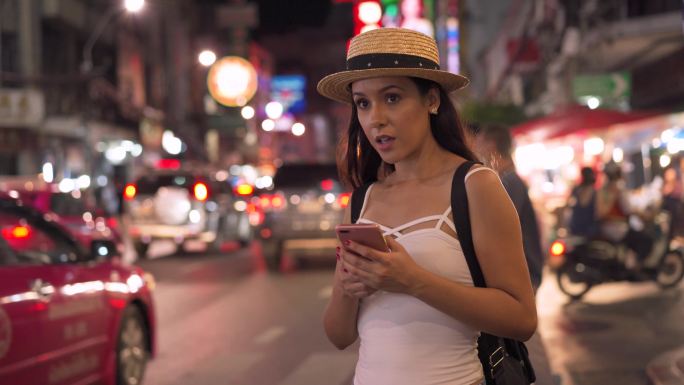 女子晚上在街道上用手机招呼出租车。