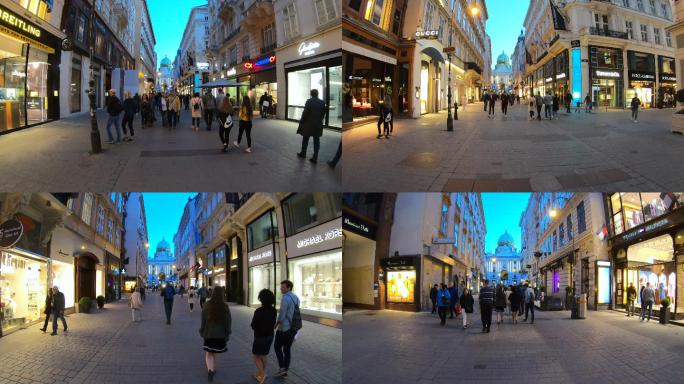 游客和居民在晚上沿着维也纳的街道散步。