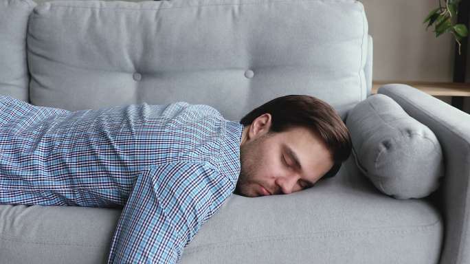 疲惫的男人下班后瘫倒在沙发上