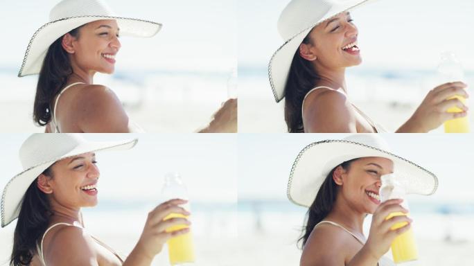 一名年轻女子在海滩放松时喝橙汁