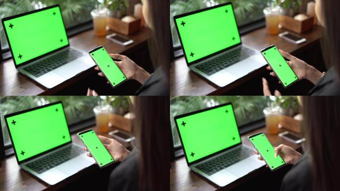 桌旁坐着手持绿色屏幕智能手机的少女