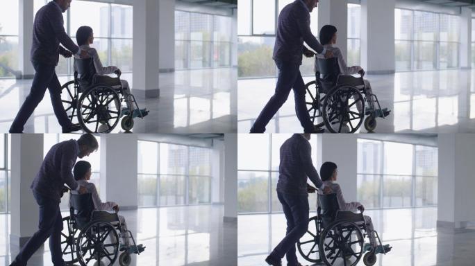 帮助残疾女孩推轮椅的父亲
