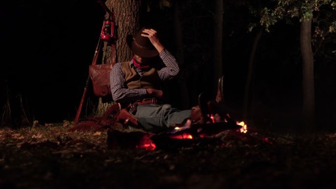 夜晚森林里靠近火堆的牛仔