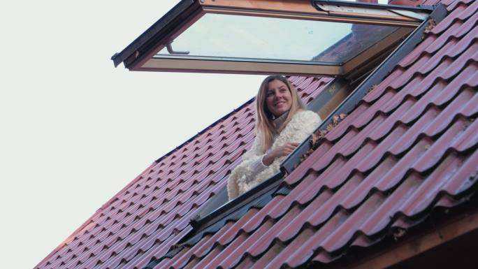 快乐的女人打开屋顶上的窗户