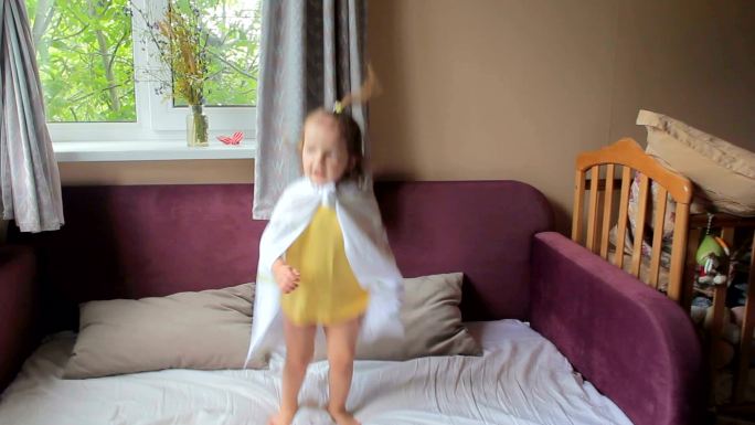可爱的小女孩在床上蹦蹦跳跳