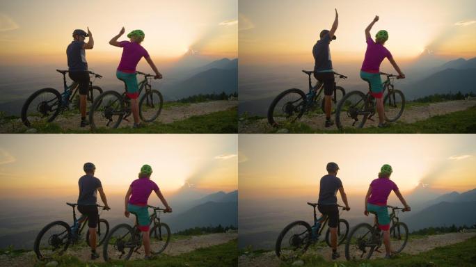 快乐的骑手坐在自行车上，在日落时分击掌