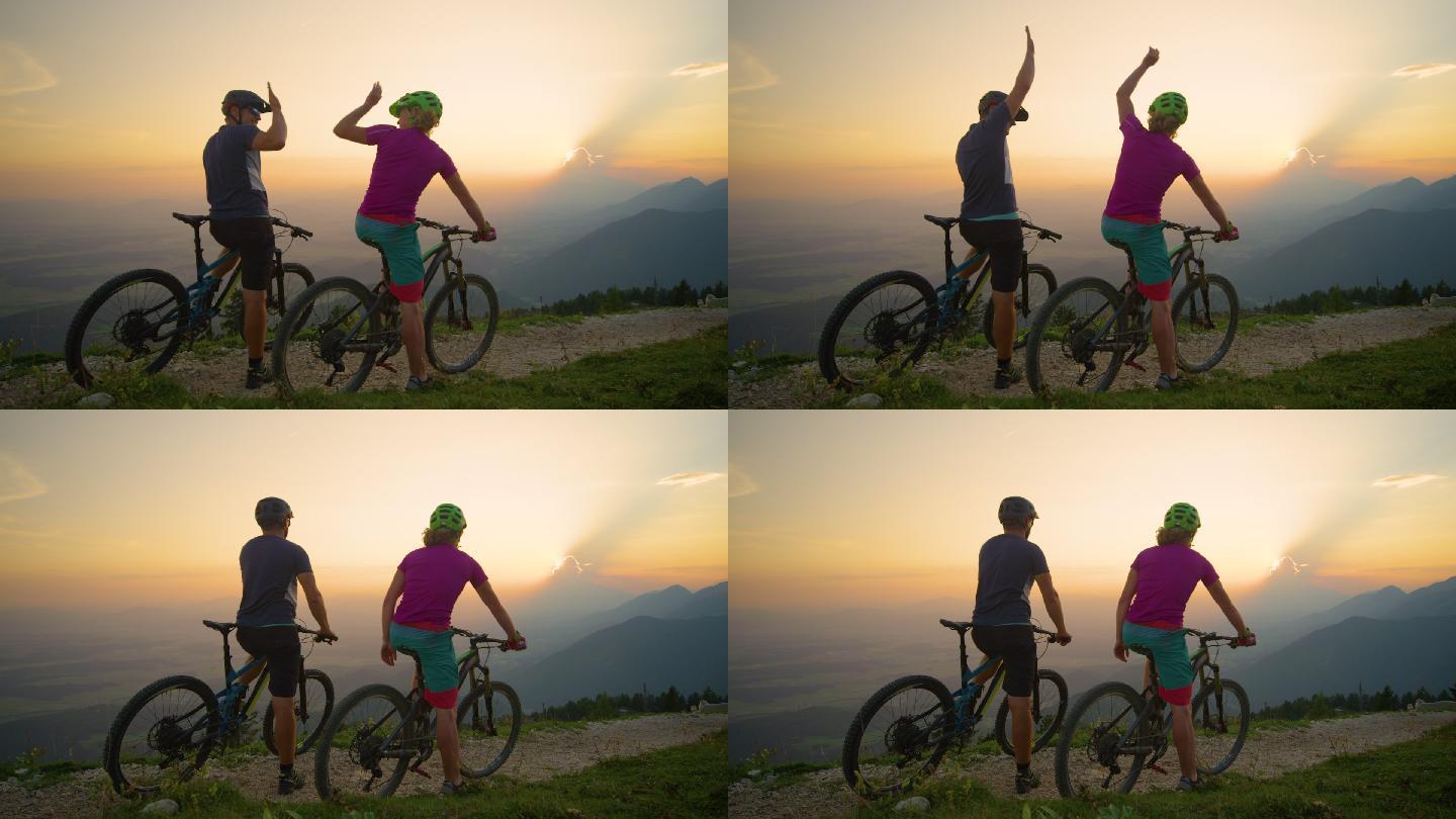 快乐的骑手坐在自行车上，在日落时分击掌