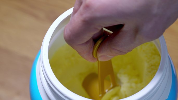 塑料罐里拿勺子舀取成人婴幼儿营养绿色奶粉