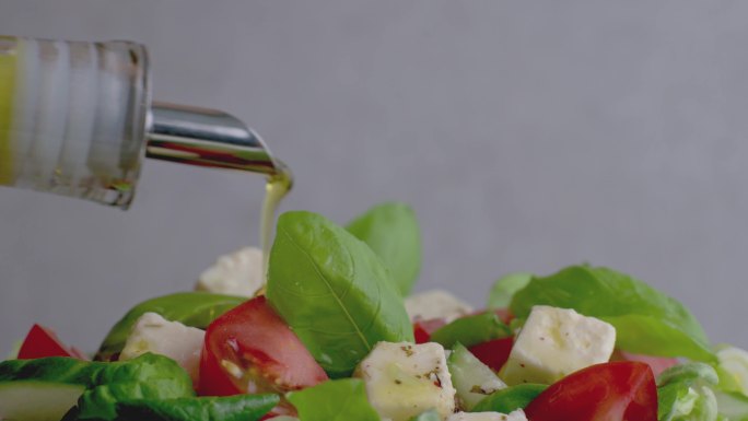 在新鲜健康的沙拉上撒上橄榄油
