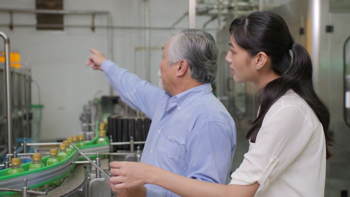工厂经理和一位女性助理在瓶子生产线讨论