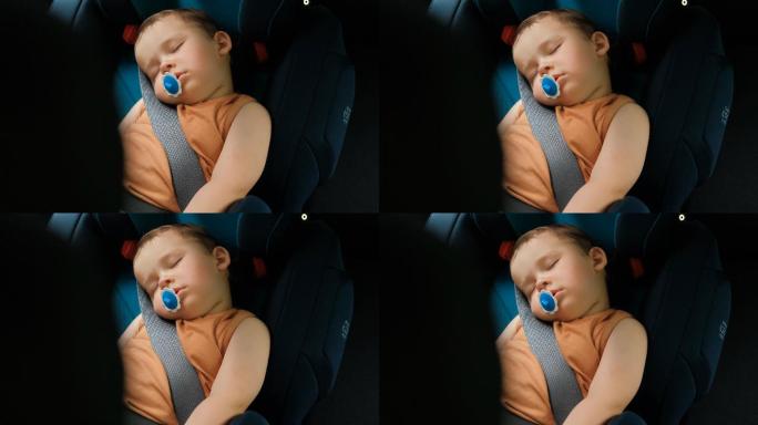 一个小男孩睡在汽车中的儿童安全座椅上