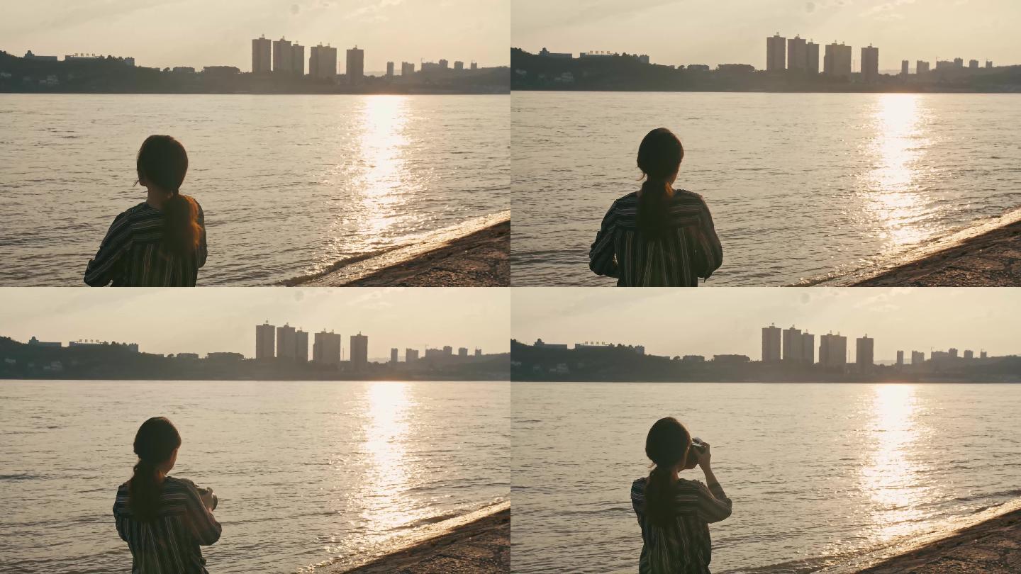 女子迎着夕阳在江边拍照