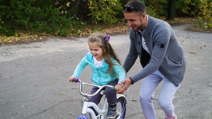 爸爸在公园教女儿骑自行车