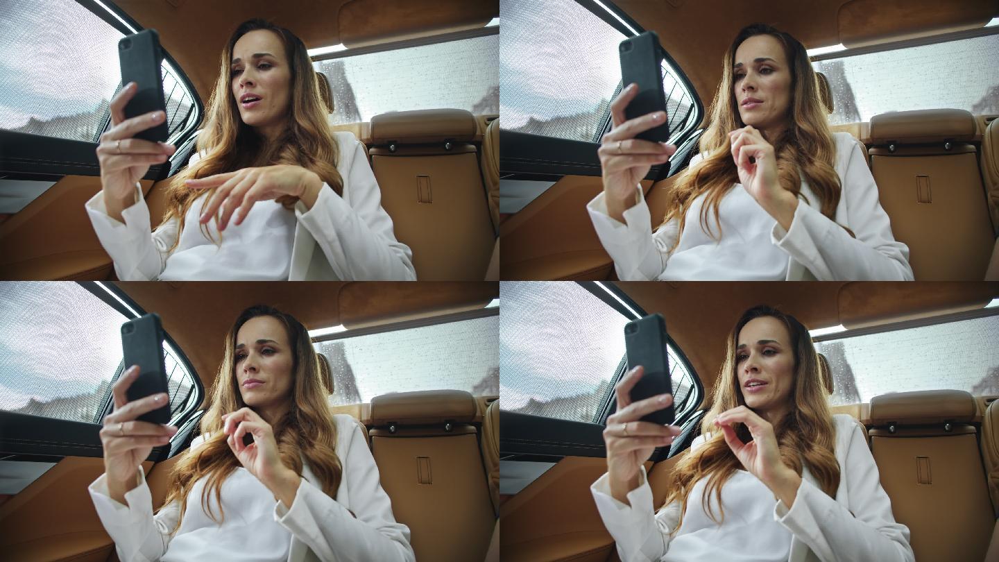 商务女士在汽车的智能手机上通过视频通话。