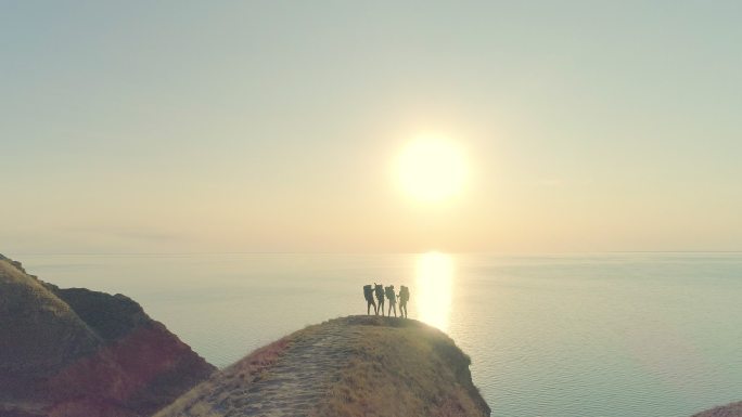 四位游客站在美丽的海洋背景下的山崖上
