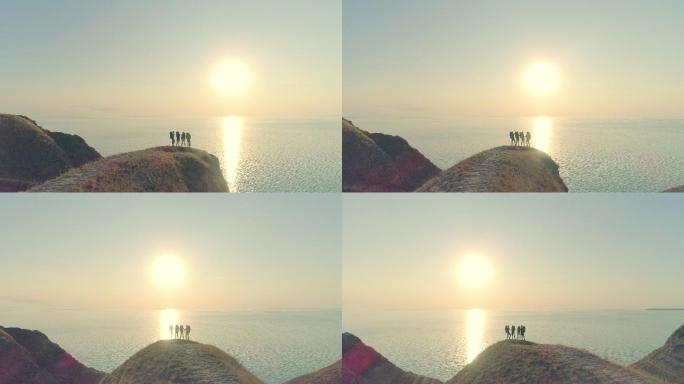 四位游客站在美丽的海洋背景下的山崖上