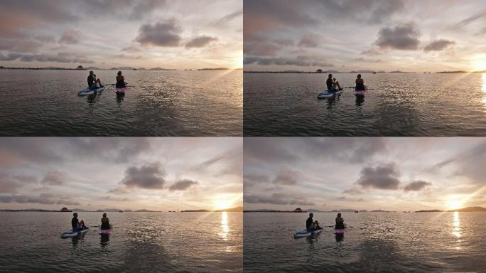 朋友们在划桨板上观看美丽的日落